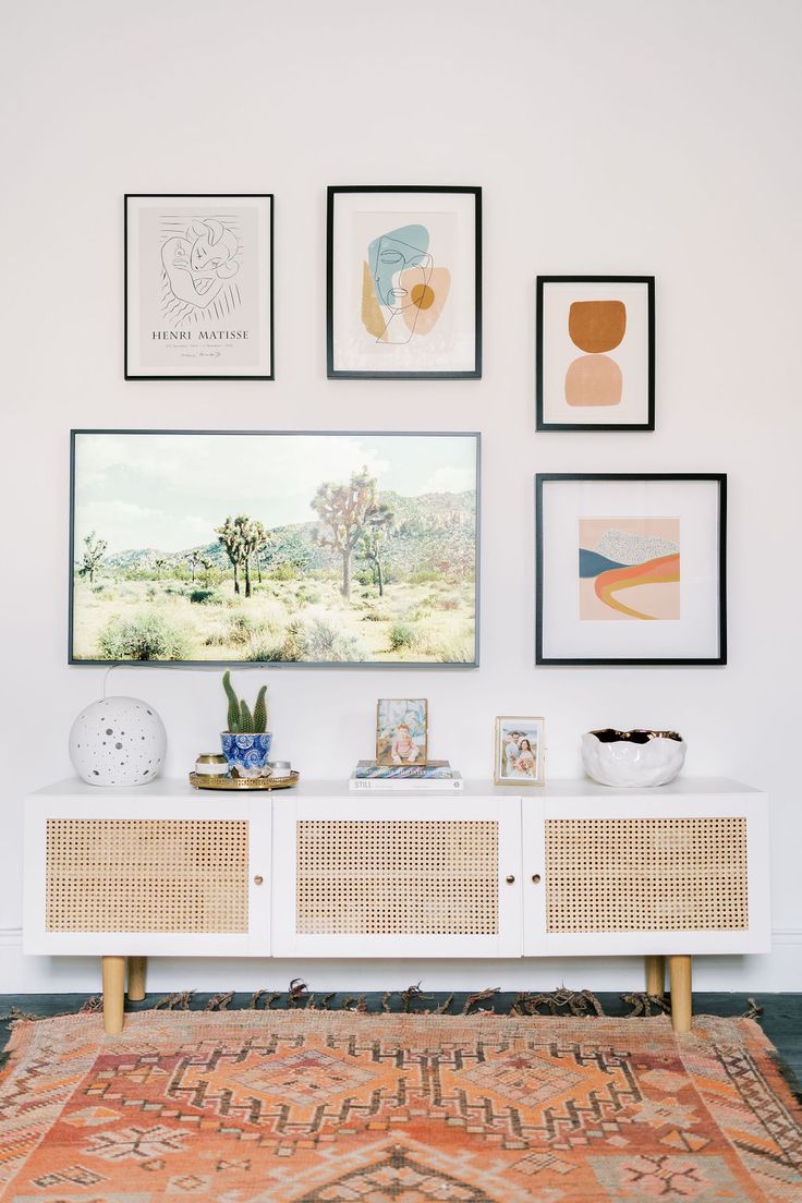 a living room with pictures hanging on the wall and a rug in front of it