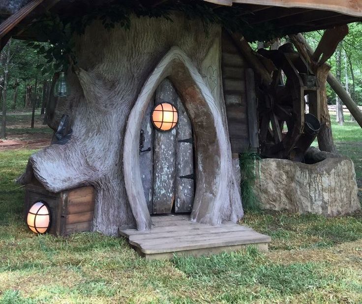 a house made out of tree trunks and logs with lights on the windows in it