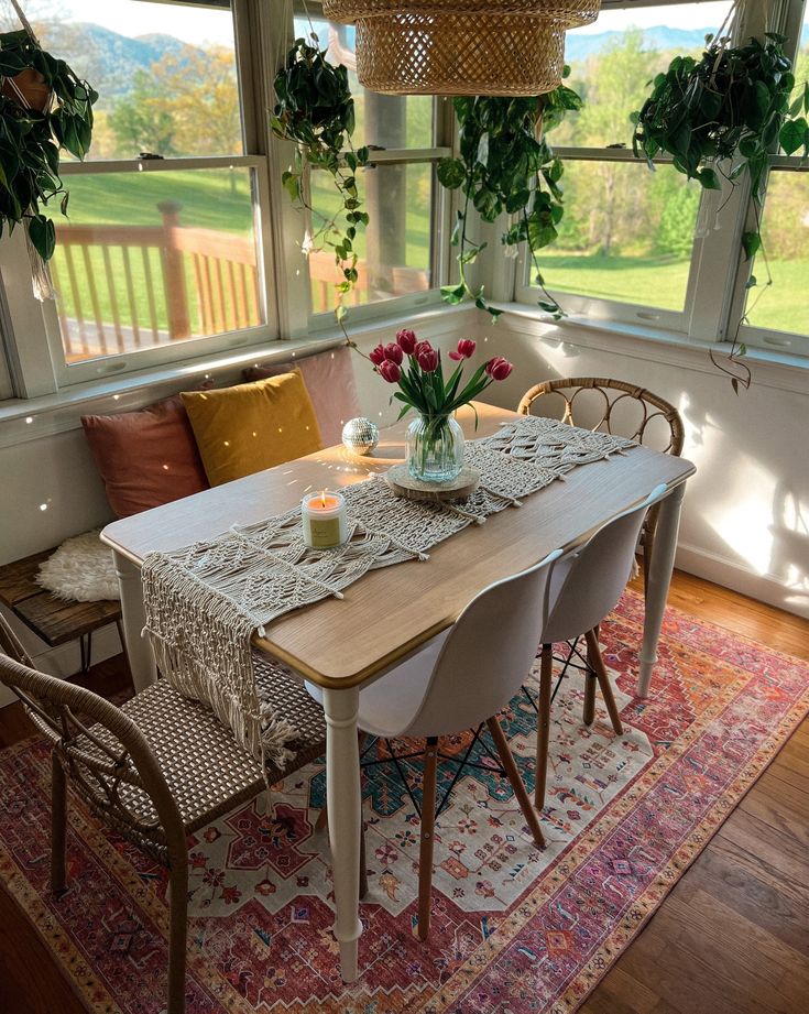 a dining room table set with place settings and flowers in vases on the table