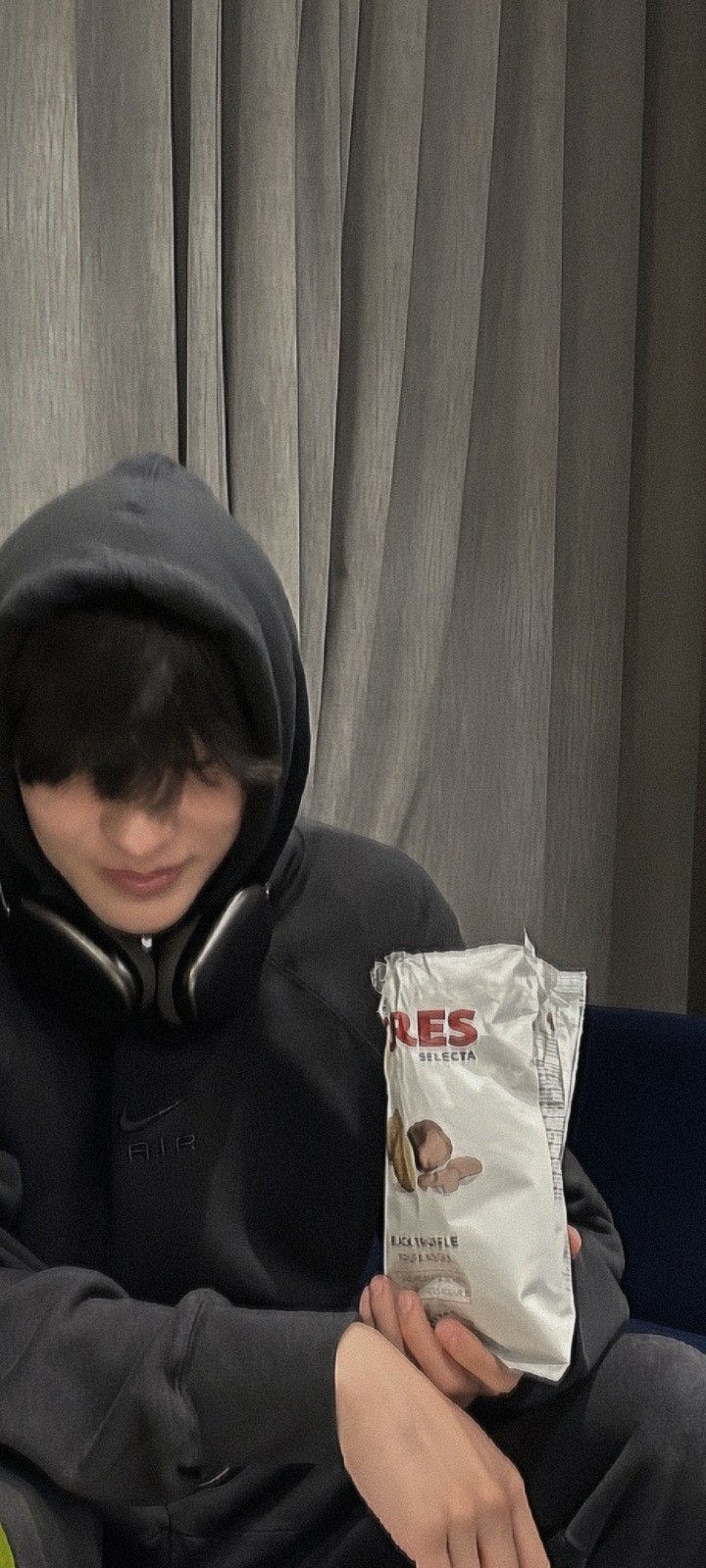 a young boy sitting on a couch holding a bag of chips