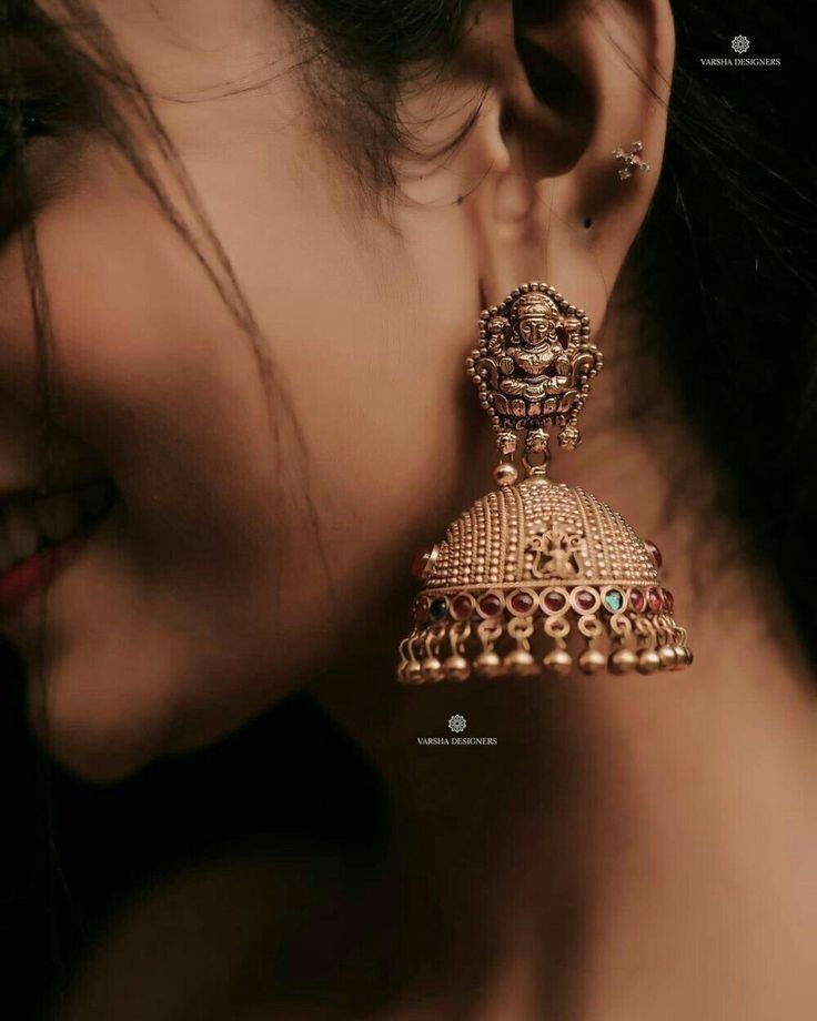 a close up of a person wearing gold ear rings and earrings with beads on them