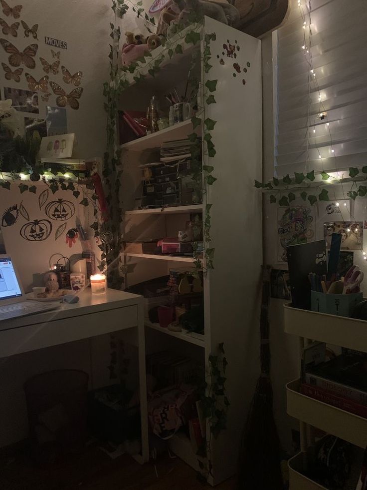 a laptop computer sitting on top of a desk next to a wall covered in vines