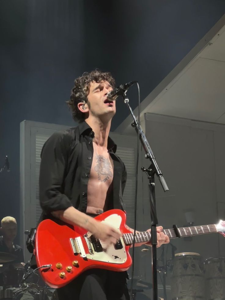 a shirtless man playing an electric guitar on stage