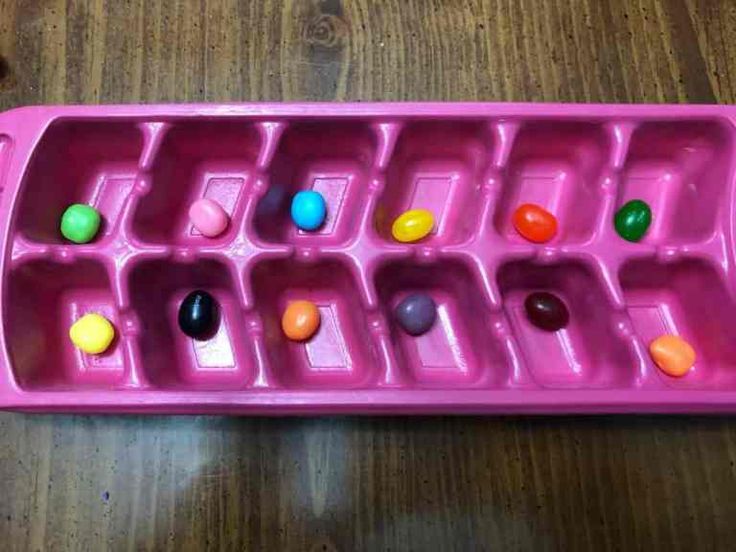 a pink plastic tray filled with lots of candies on top of a wooden table