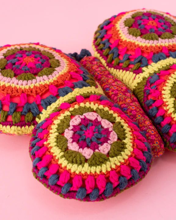 four crocheted round cushions sitting on top of a pink surface