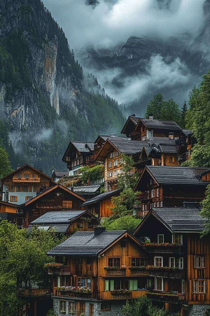 a group of wooden buildings sitting on top of a lush green hillside covered in clouds