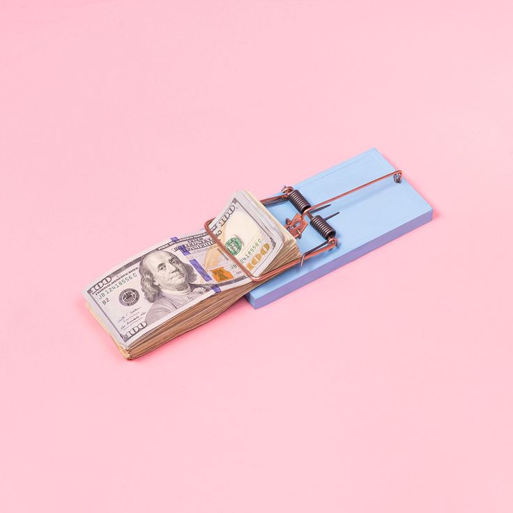 a mouse trap with money in it sitting on a pink and blue pad against a pink background