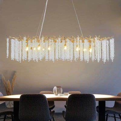 a chandelier hanging over a dining room table with four chairs and two vases