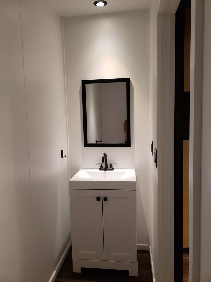 a bathroom with a sink, mirror and cupboards on the wall next to it