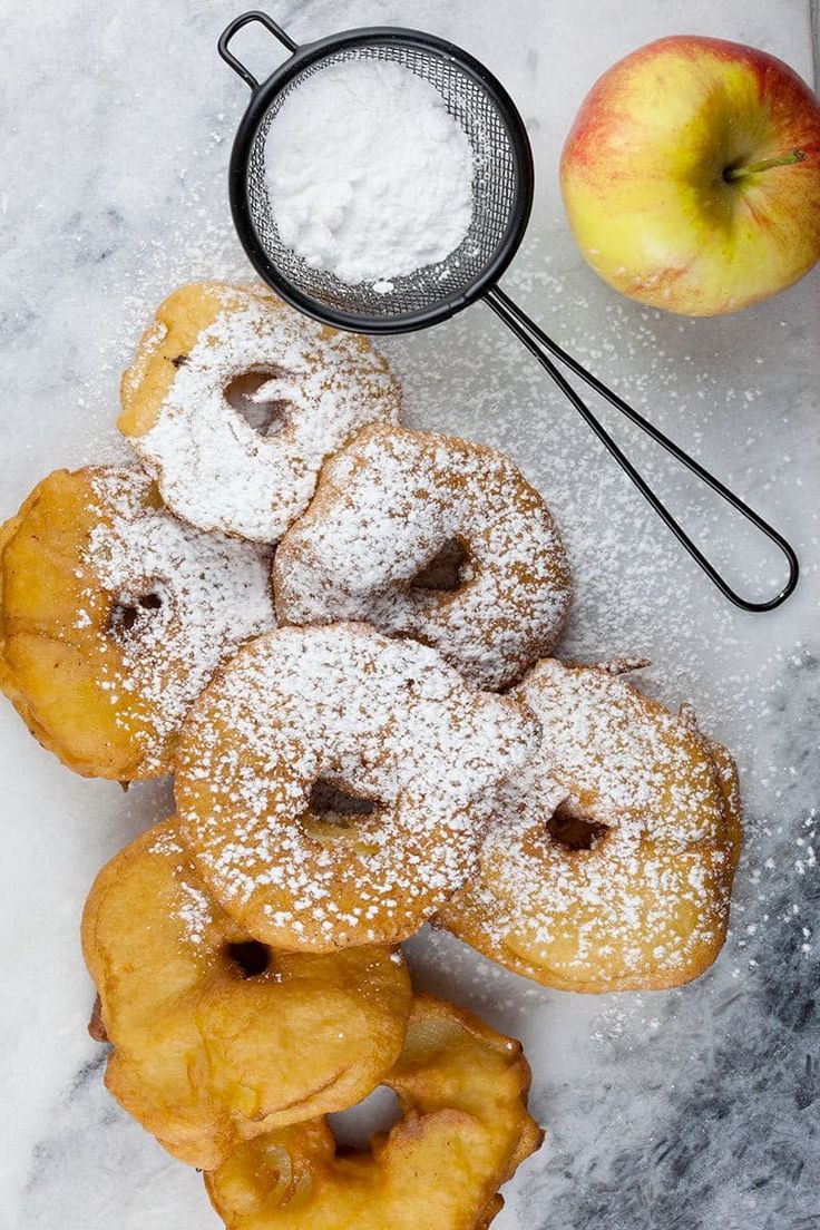 powdered sugar covered donuts next to an apple