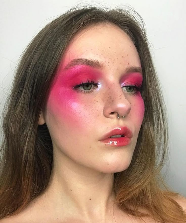 a woman with bright pink makeup and freckles on her face is looking at the camera