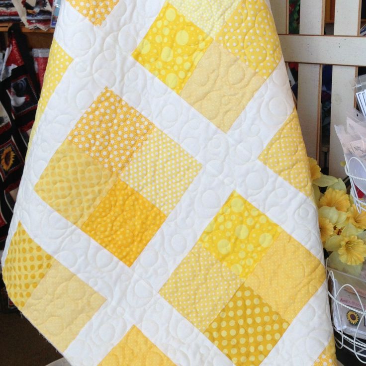 a yellow and white quilt sitting on top of a chair