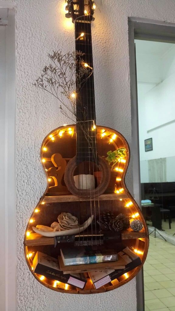 a guitar hanging on the wall with lights around it