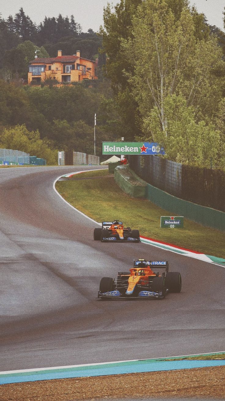 two racing cars on a race track with trees in the background