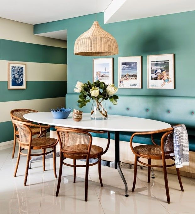 a dining room with blue and white striped walls, wicker chairs and a round table