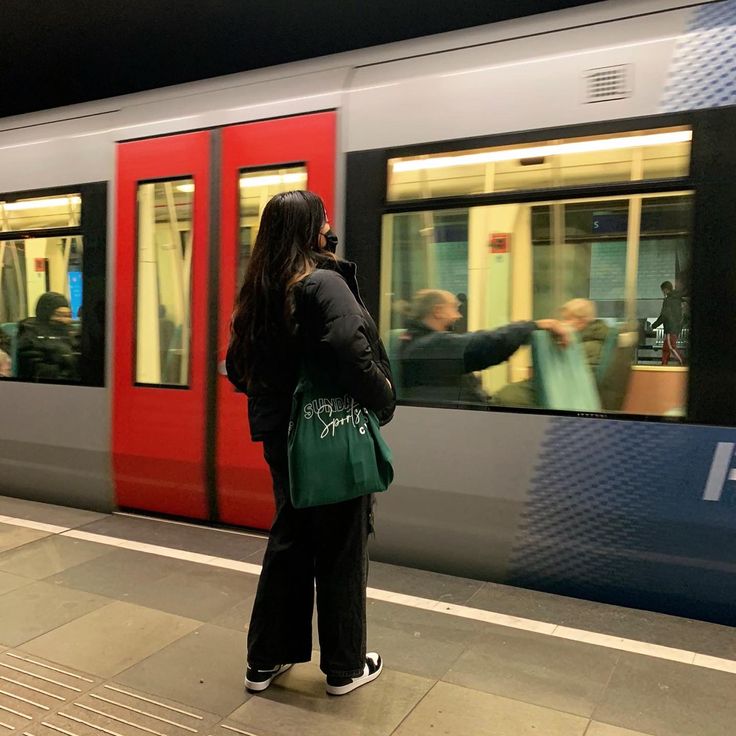 a woman standing in front of a subway train