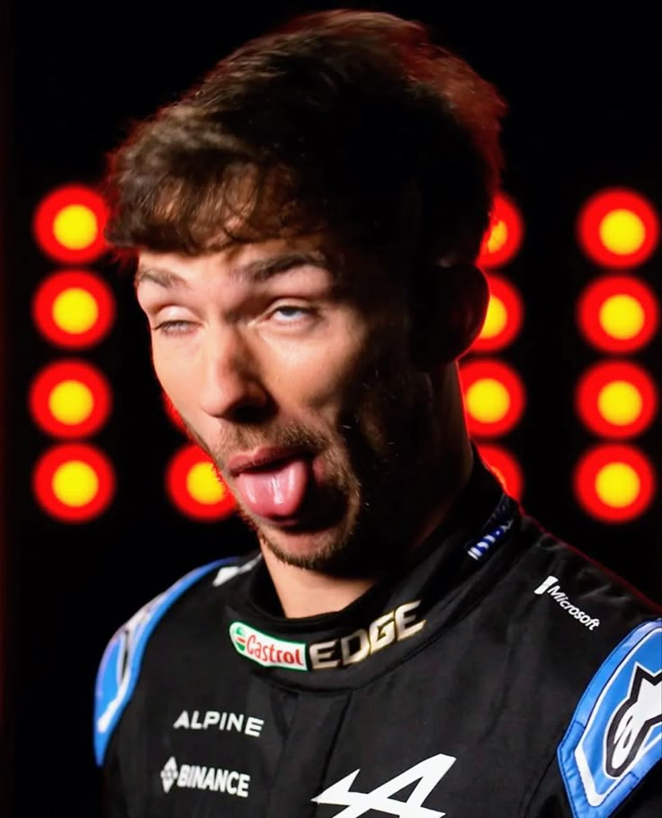 a close up of a person making a funny face with his tongue out and lights in the background