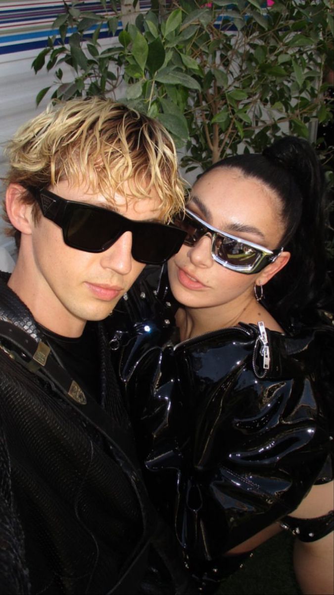 two people wearing black clothing and sunglasses posing for the camera