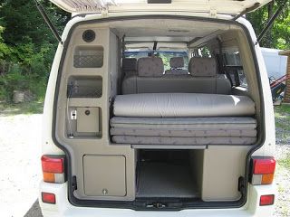 the back end of a white van with its doors open and seats folded up in place