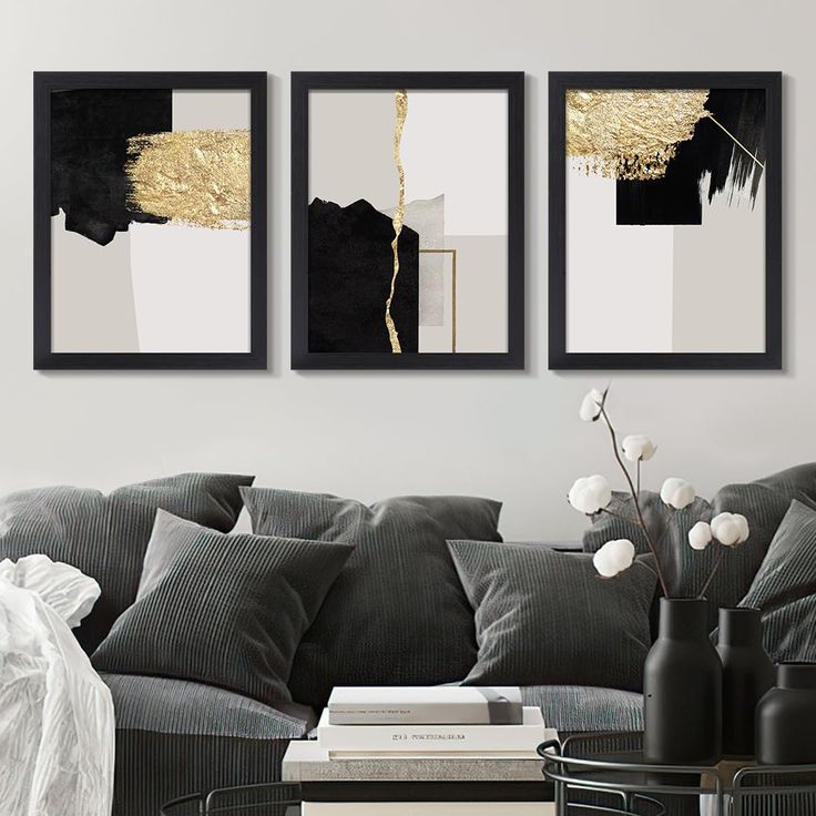 three black and white paintings hanging on the wall above a gray couch in a living room