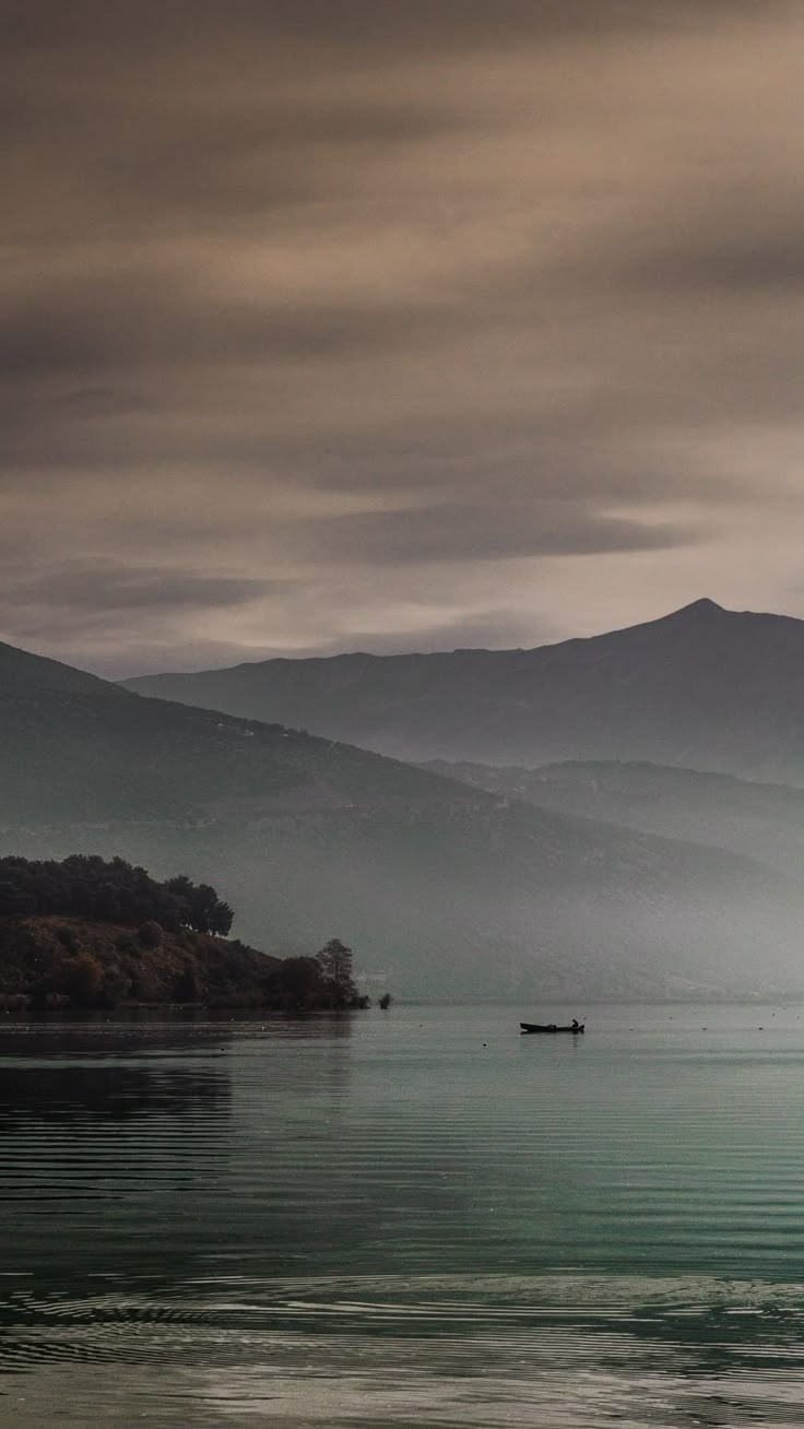 two boats floating on top of a large body of water under a dark cloudy sky