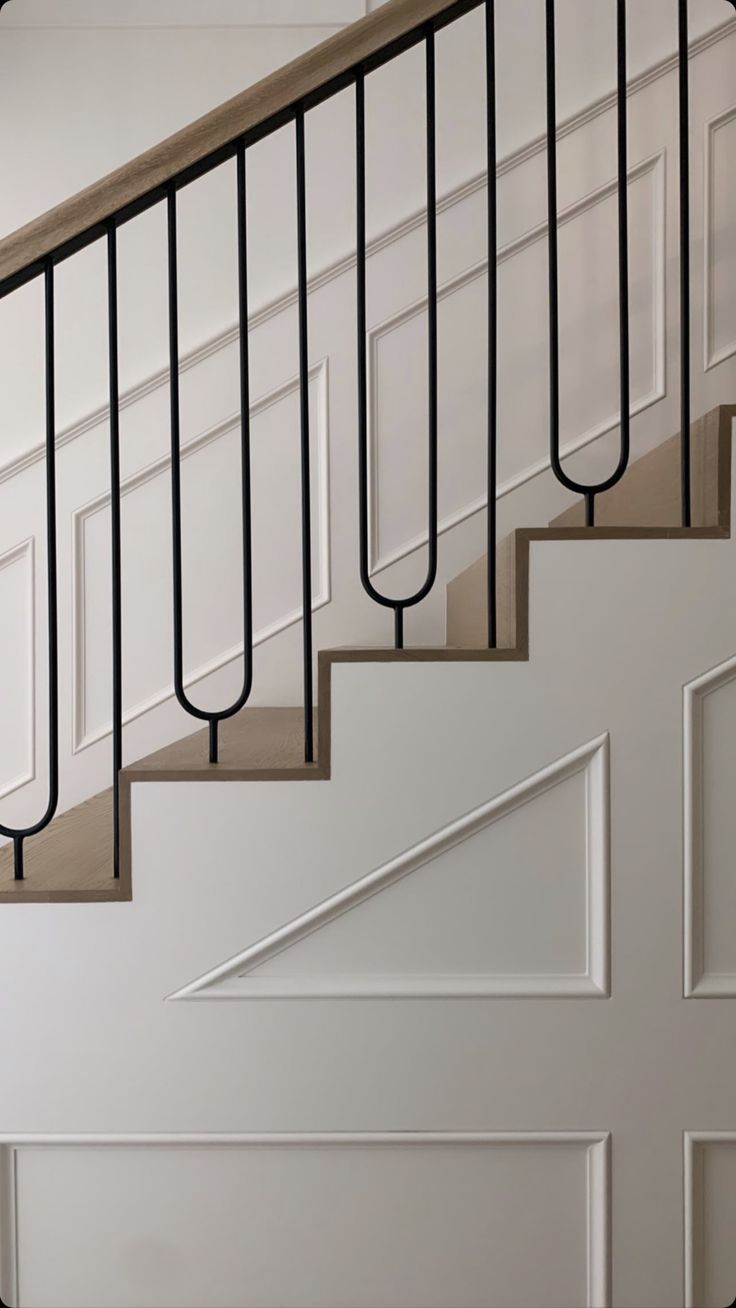 a white staircase with black handrails next to a door in a home's entryway