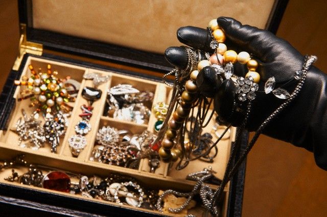 a person's hand holding a bunch of necklaces and bracelets in a box