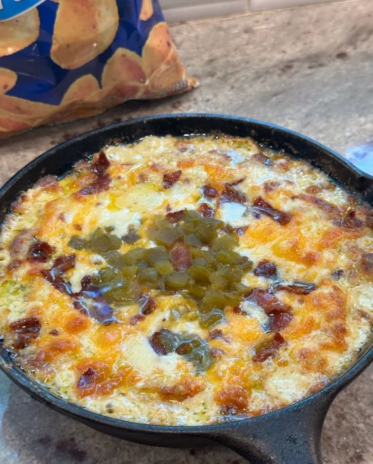 an omelet with cheese and green peppers in a cast iron skillet next to chips