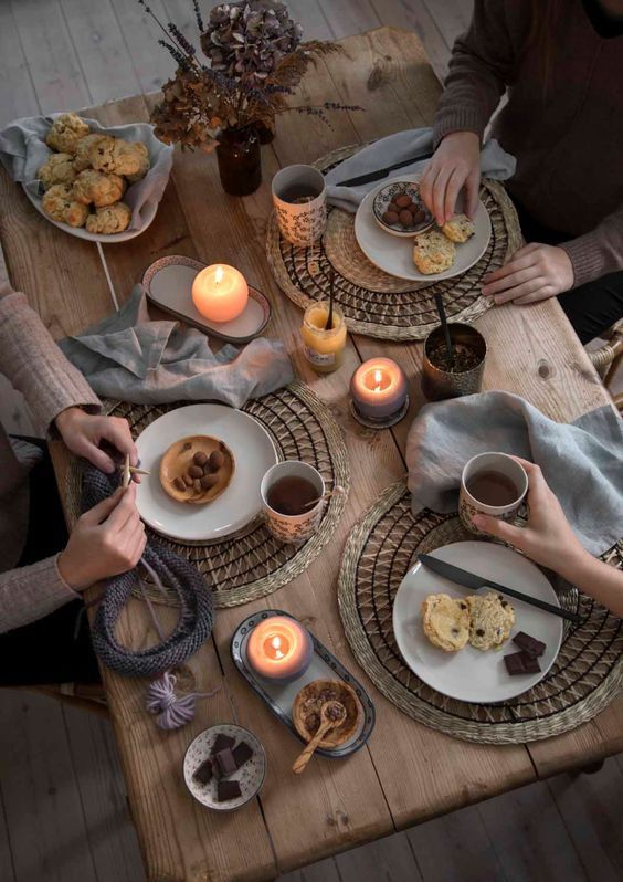 two people sitting at a table with plates of food and candles in front of them