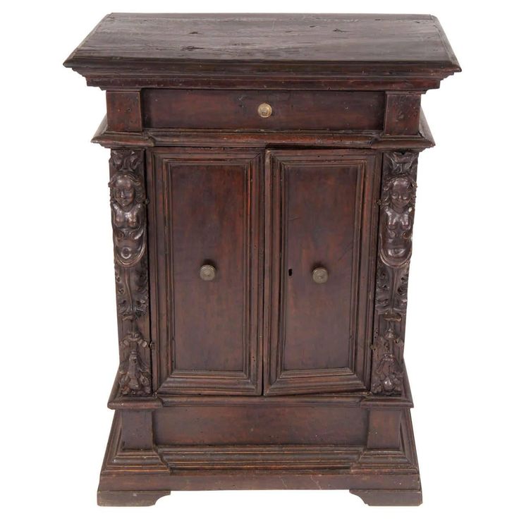 an old wooden cabinet with two doors and carvings on the front, sitting against a white background