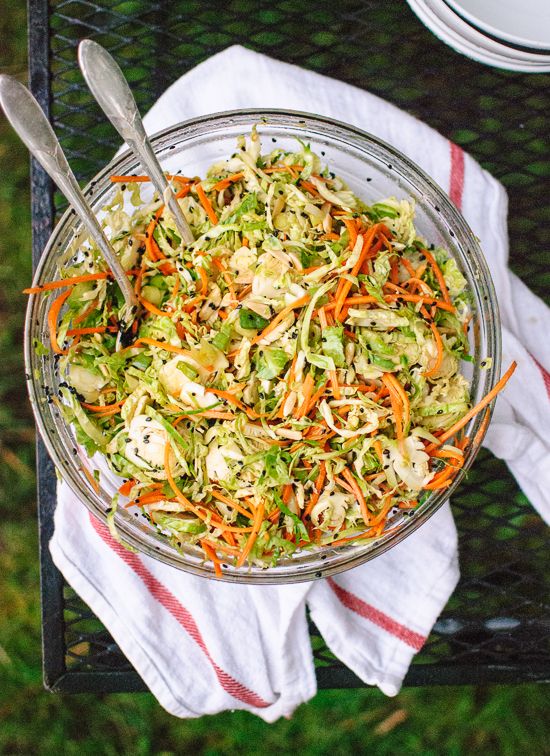 a glass bowl filled with coleslaw and carrots on top of a table