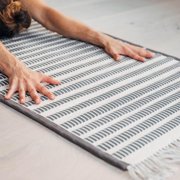 a woman laying on top of a rug with her hands resting on the floor next to it