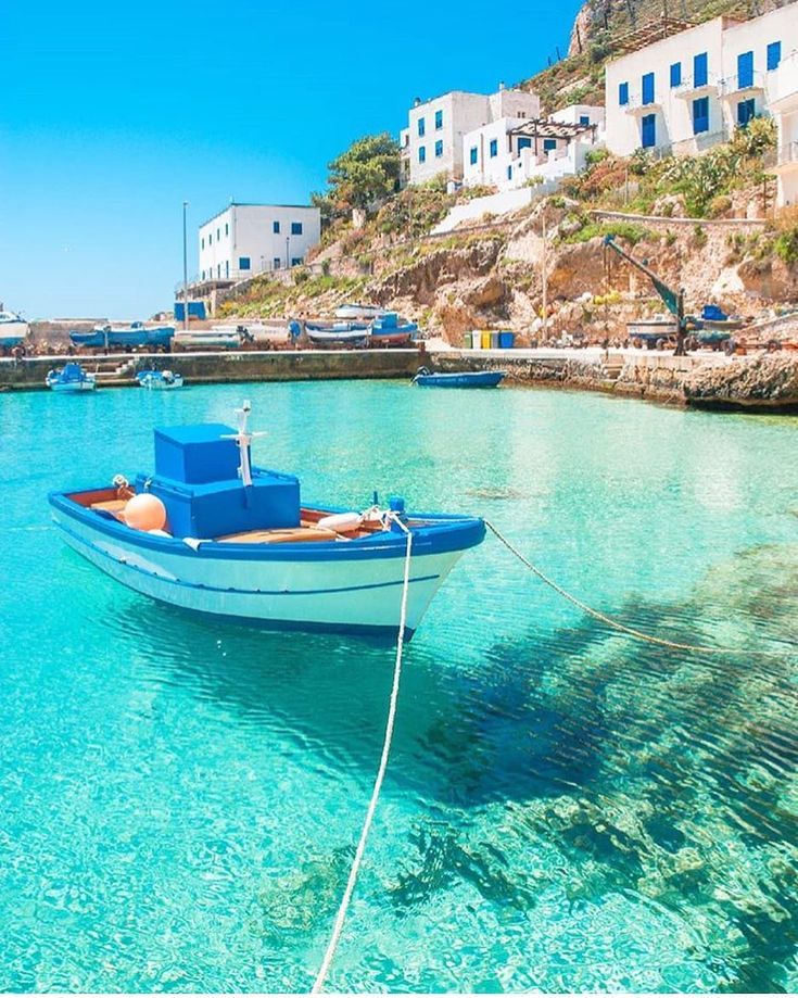 a small boat floating on top of a blue body of water next to a beach