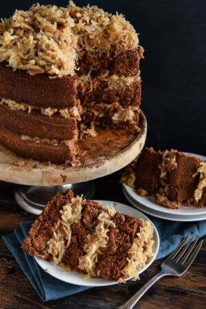 a chocolate cake with coconut frosting is on a plate and next to the rest of the cake