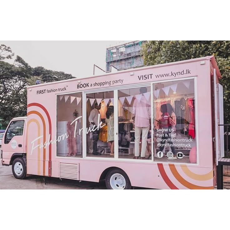 a pink food truck parked in front of a building