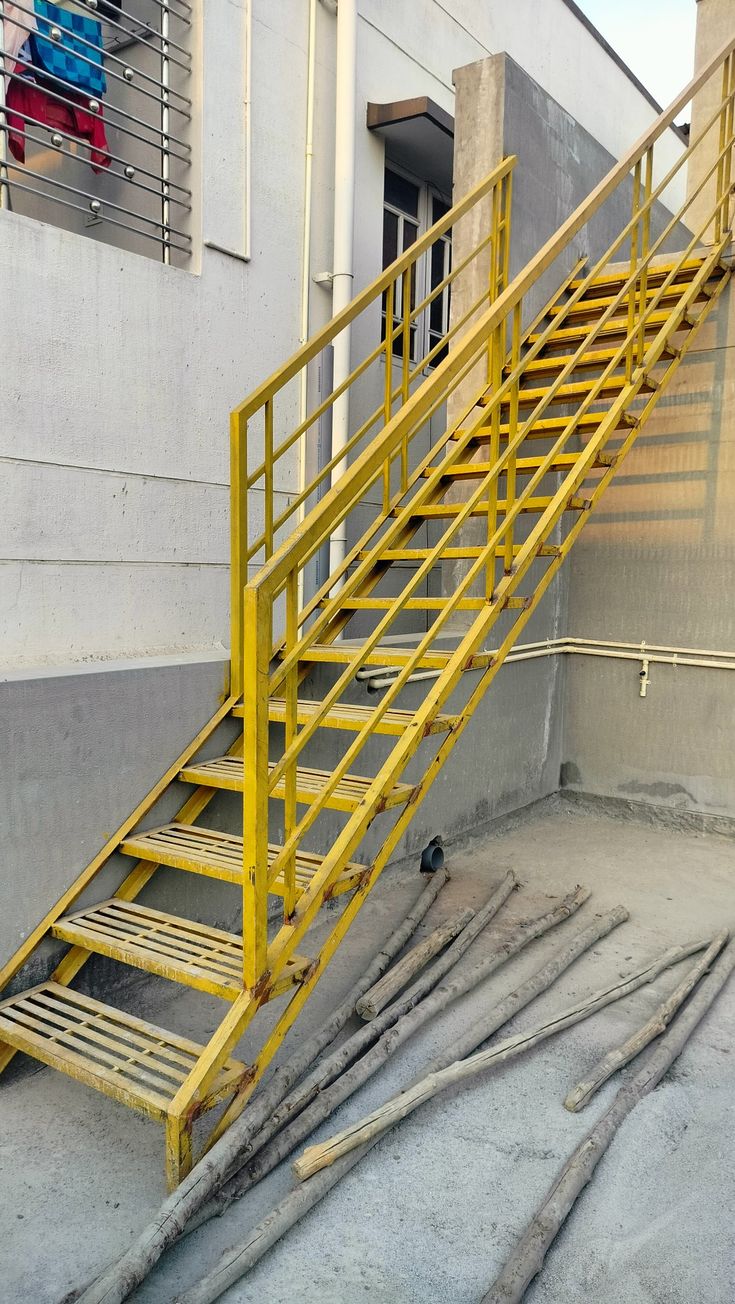 there is a yellow metal stair case on the side of a building that has been knocked over