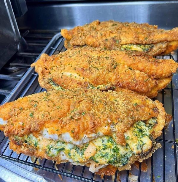 two pieces of fried chicken sitting on top of an oven rack with broccoli and cheese