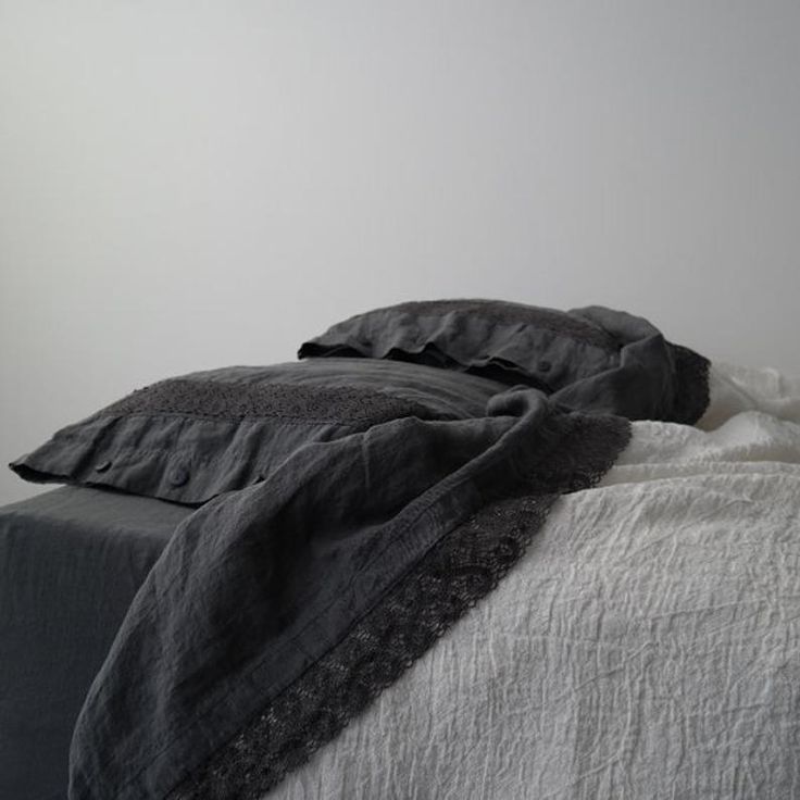 an unmade bed with black and white linens