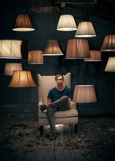 a man sitting in a chair surrounded by lamps