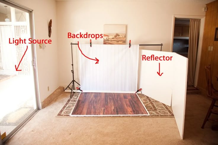 an empty room with white backdrop and wood flooring