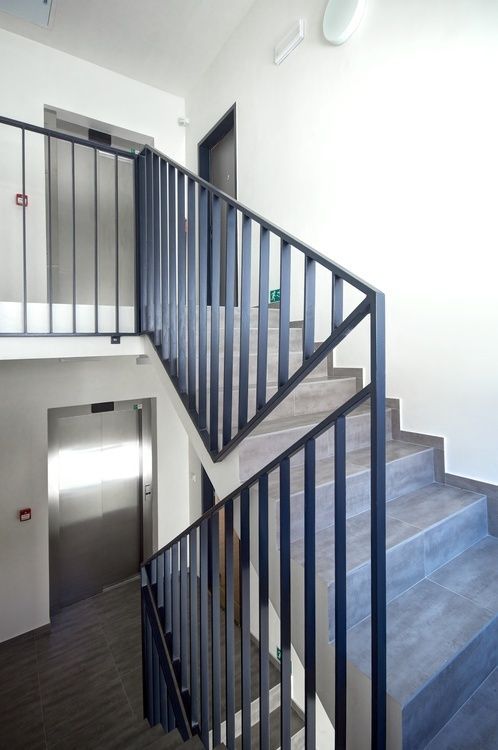 the stairs are made of metal and wood, leading up to an open door on the second floor