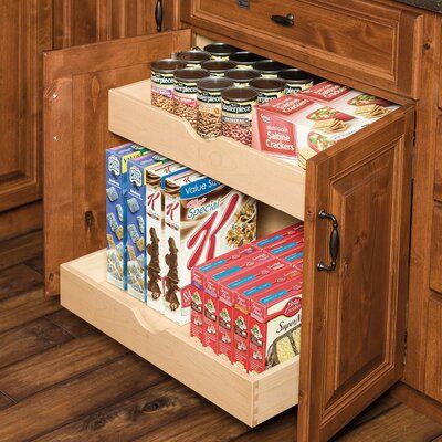 an open drawer in the middle of a kitchen with wooden cabinets and wood flooring