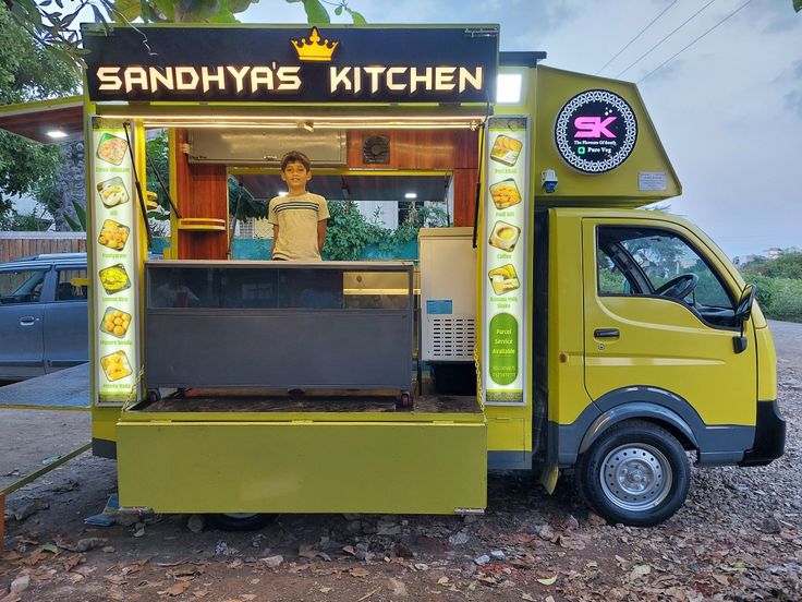 a man standing in front of a yellow food truck with lights on it's side