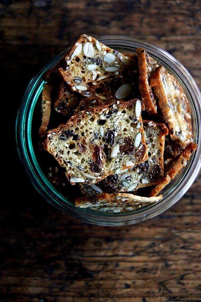 a glass jar filled with toasted bread and raisins on top of a wooden table