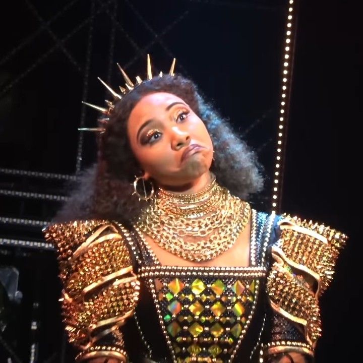 a woman wearing gold and black jewelry on stage