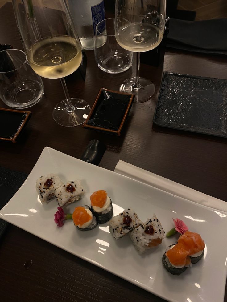 sushi on a plate with wine glasses in the background