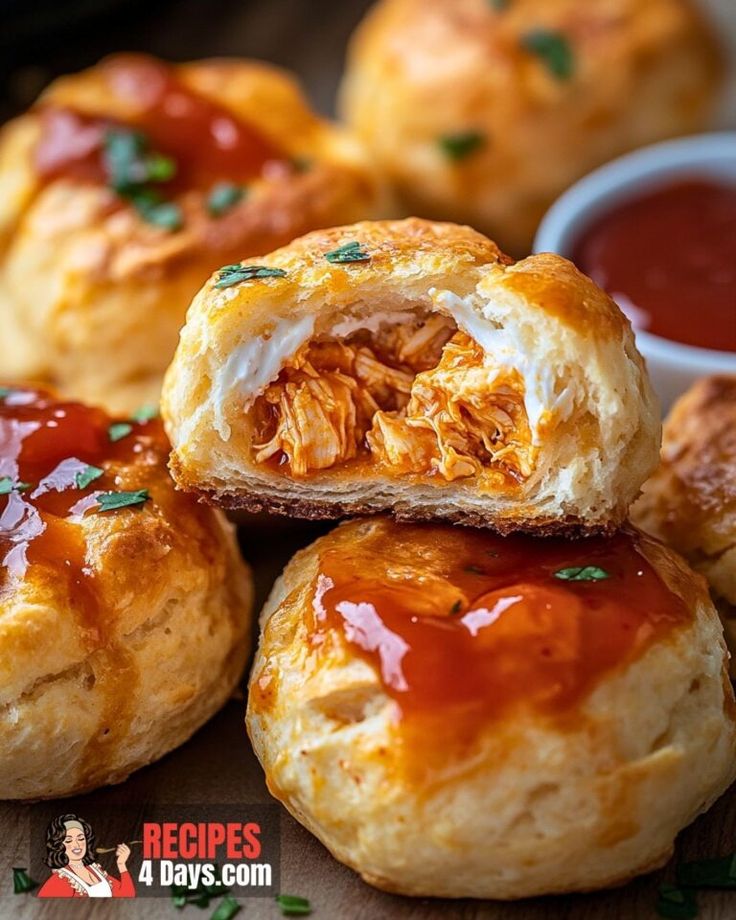 several puffy pastries with ketchup and sauce on them sitting on a cutting board