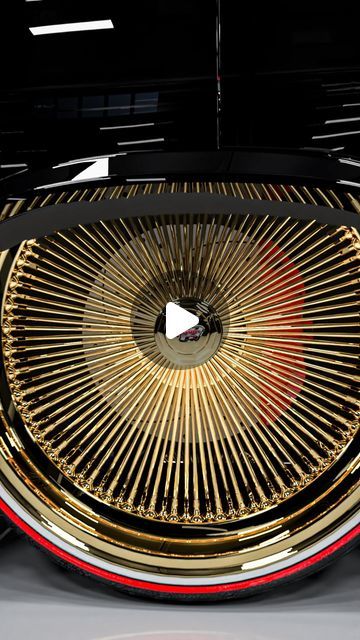 the front end of a black car with gold spokes and red stripeing on it