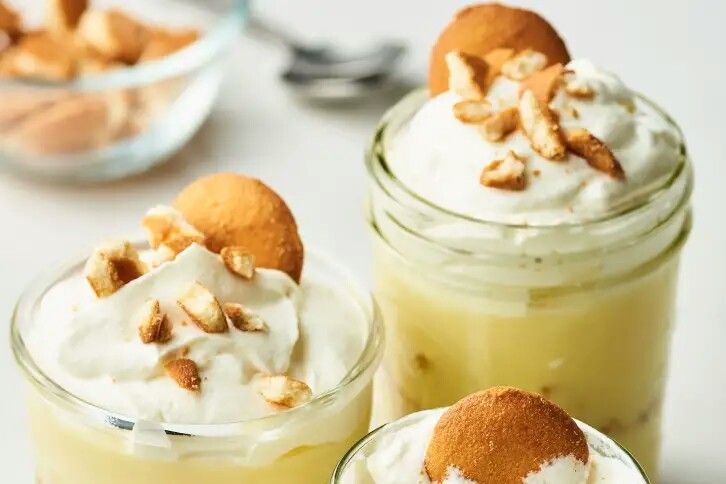 three desserts in small glass jars on a table