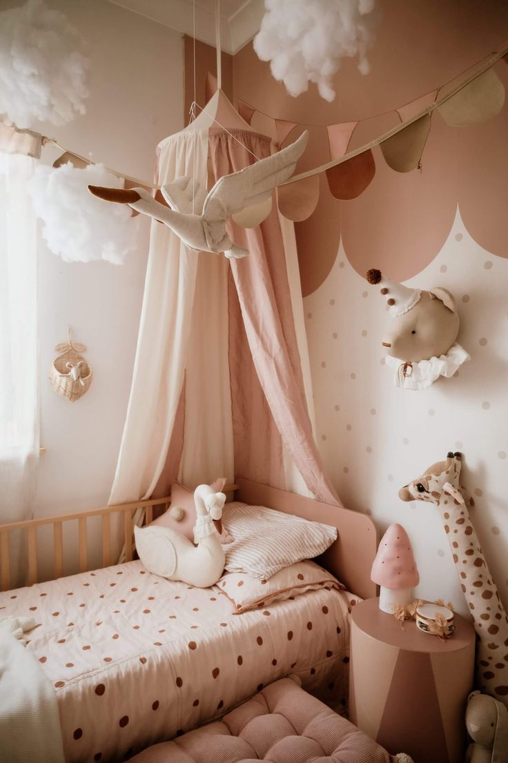 a child's bedroom with pink and white decorations on the walls, teddy bears hanging above the bed